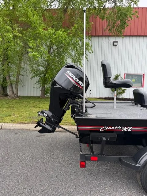 Slide: The Image of 2025 Tracker Bass Tracker Classic XL boat with Mercury outboard motor, parked outdoors. - 6