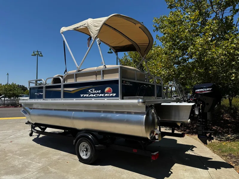 Slide: The Image of 2025 Sun Tracker Bass Buggy 16 XL Select pontoon boat with canopy and Mercury outboard motor. - 2
