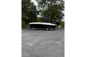 The Image of 2025 Tahoe T21 boat on trailer, parked outdoors with trees in the background. - 0