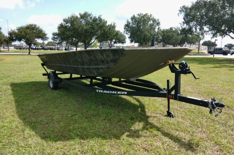 Slide: The Image of 2025 Tracker Grizzly 1860 Utility boat on trailer, parked on grassy area with trees. - 27