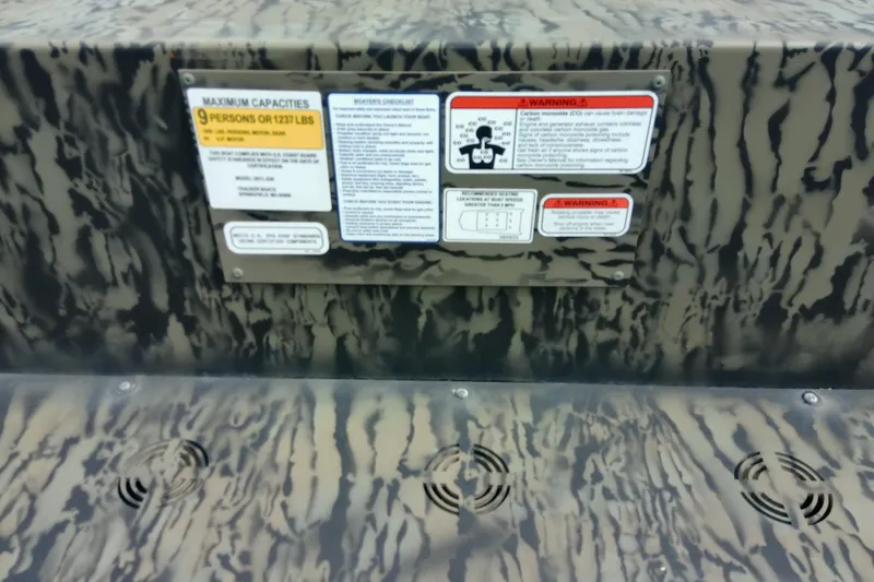 Slide: The Image of 2025 Tracker Grizzly 1860 Utility boat capacity and safety warning labels on camouflage surface. - 32