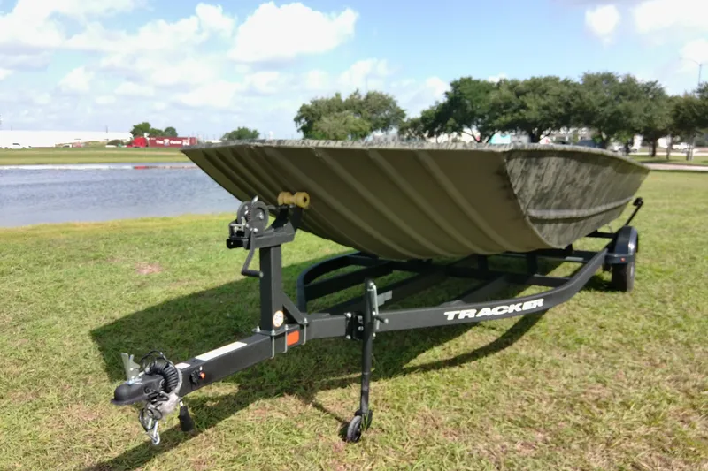 Slide: The Image of 2025 Tracker Grizzly 1860 Utility boat on trailer by a lake, grassy area. - 19