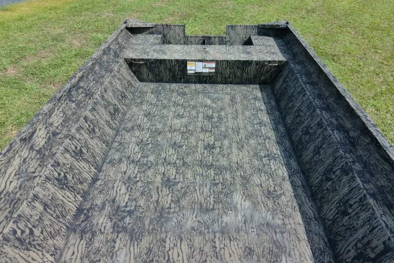 Slide: The Image of 2025 Tracker Grizzly 1860 Utility boat interior with camouflage pattern on grassy background. - 29