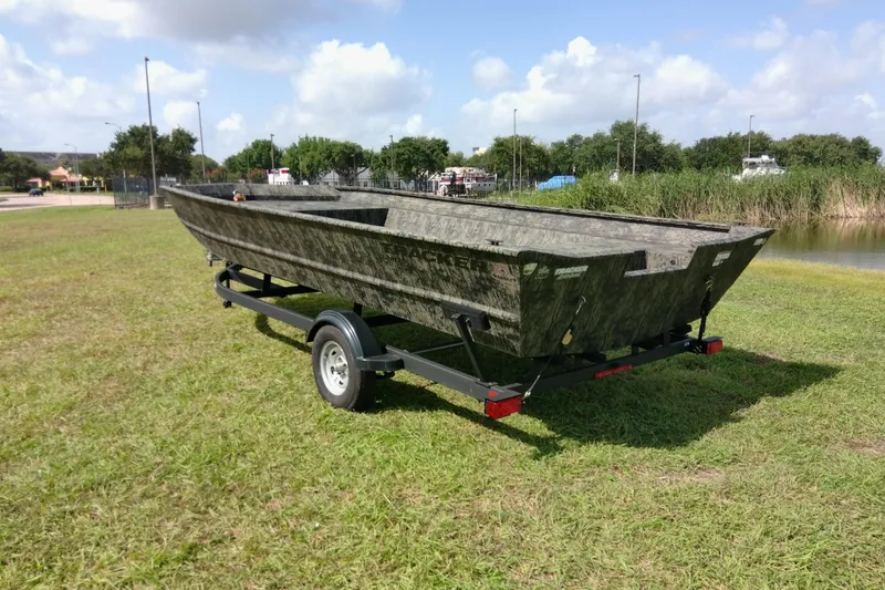 Slide: The Image of 2025 Tracker Grizzly 1860 Utility boat on trailer, parked on grassy field. - 22