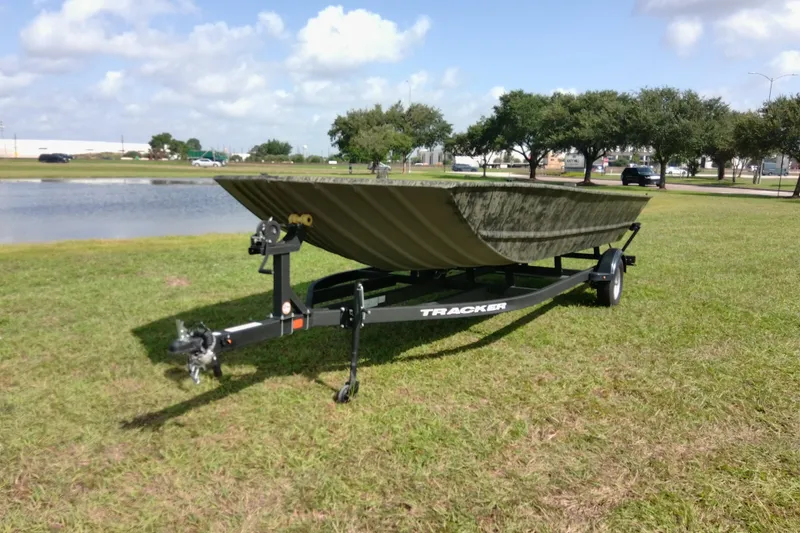 Slide: The Image of 2025 Tracker Grizzly 1860 Utility boat on trailer by a pond, grassy area. - 20