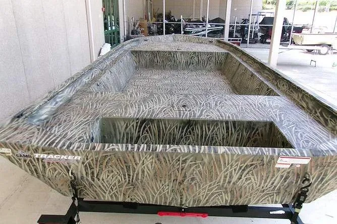 Slide: The Image of 2025 Tracker Grizzly 1860 Utility boat with camouflage design in a showroom setting. - 4