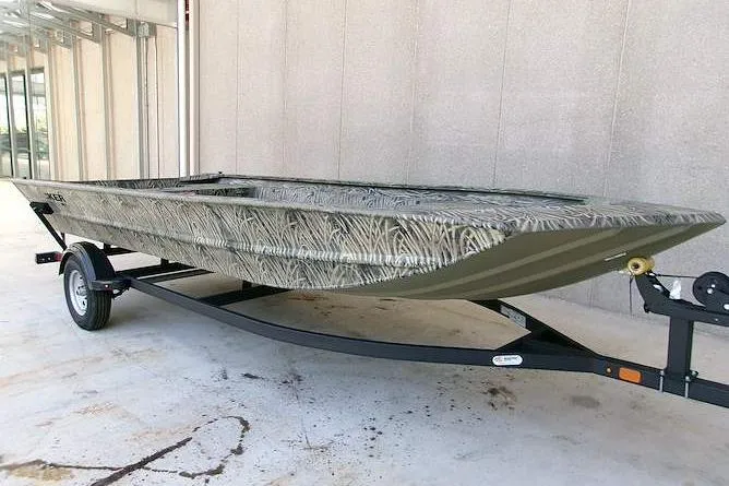 The Image of 2025 Tracker Grizzly 1860 Utility boat on trailer, camo design, parked indoors. - 0