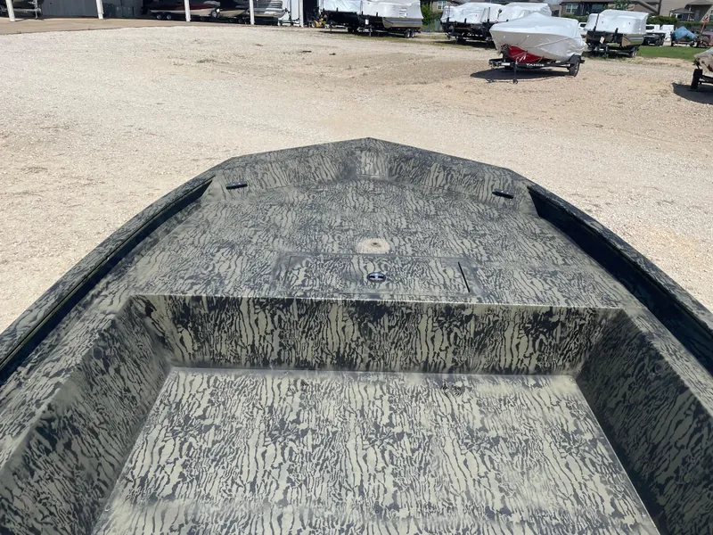 Slide: The Image of 2025 Tracker GRIZZLY 1860 Utility boat with camouflage pattern, parked on gravel. - 11