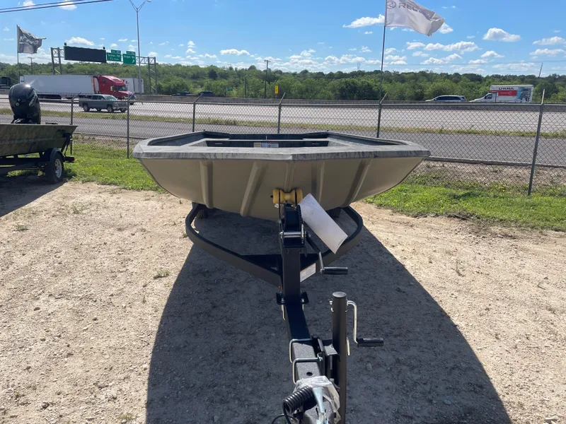 Slide: The Image of 2025 Tracker GRIZZLY 1860 Utility boat on trailer, parked outdoors near highway. - 2