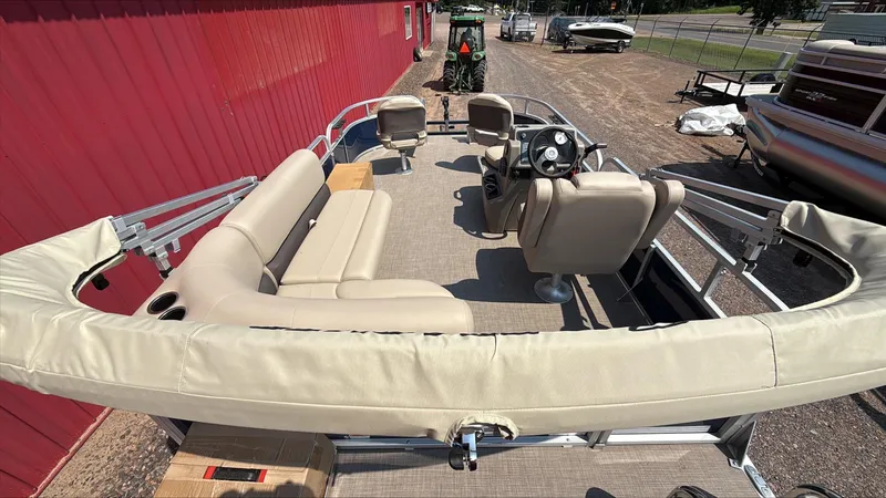 Slide: The Image of 2025 Sun Tracker Bass Buggy 16 XL Select pontoon boat with beige seating and steering console. - 2