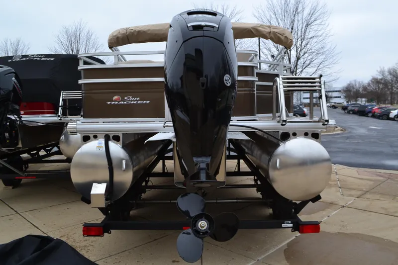 Slide: The Image of 2025 Sun Tracker SportFish 20 DLX pontoon boat, rear view with motor, parked outdoors. - 3