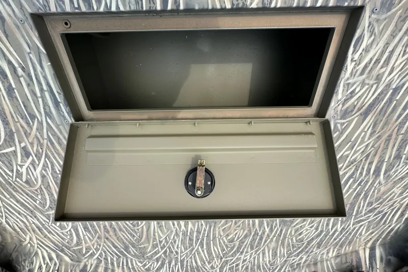 Slide: The Image of 2025 Tracker Grizzly 1860 Utility storage compartment with camouflage pattern and secure latch. - 21