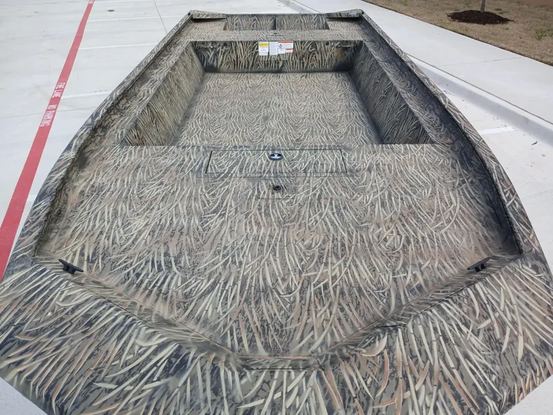 Slide: The Image of 2025 Tracker GRIZZLY 1860 Utility boat with camouflage design on concrete surface. - 2