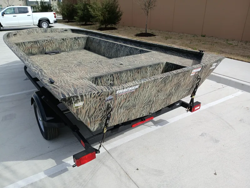 Slide: The Image of 2025 Tracker GRIZZLY 1860 Utility boat on trailer, camo design, parked outdoors. - 4