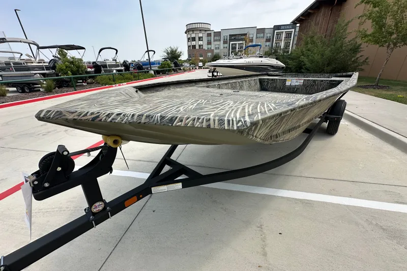 Slide: The Image of 2025 Tracker Grizzly 1860 Utility boat on trailer, parked outdoors. - 18