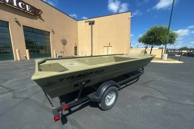 Slide: The Image of 2025 Tracker Grizzly 1860 Utility boat on trailer, parked outside a building under a clear sky. - 3