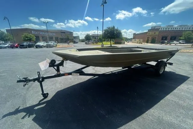 Slide: The Image of 2025 Tracker Grizzly 1860 Utility boat on trailer in parking lot under blue sky. - 2