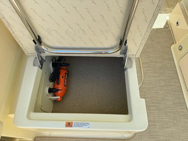 Slide: The Image of Storage compartment in 2025 Chris-Craft Calypso 28 boat with an orange power tool inside. - 17