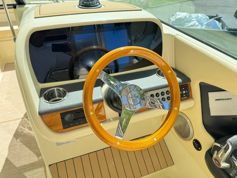 Slide: The Image of 2025 Chris-Craft Calypso 28 helm with wooden steering wheel and modern controls. - 21
