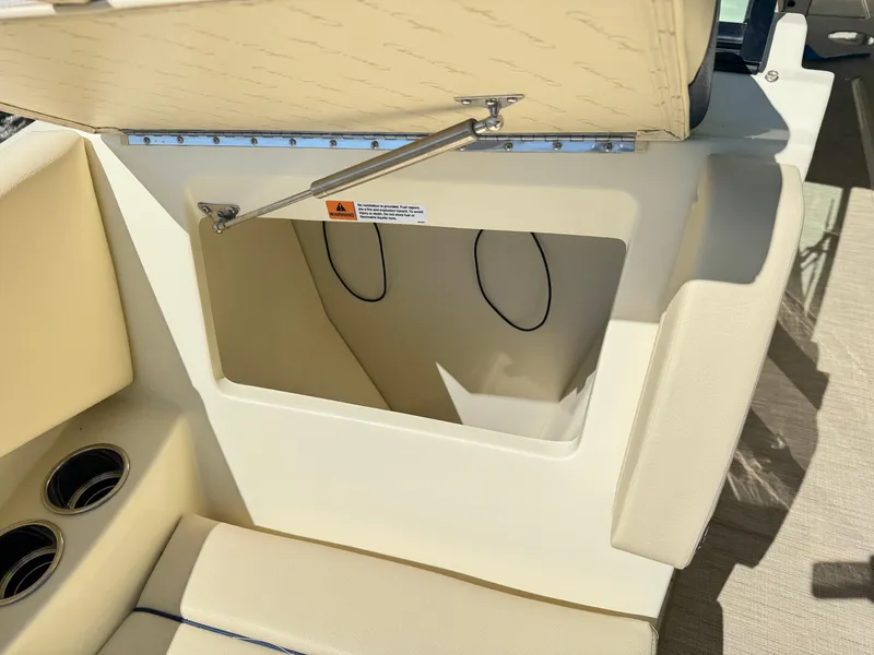 Slide: The Image of 2025 Chris-Craft Calypso 28 boat storage compartment with beige seating and cup holders. - 29