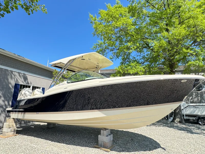 Slide: The Image of 2025 Chris-Craft Calypso 28 boat displayed outdoors on blocks, under a clear blue sky. - 3