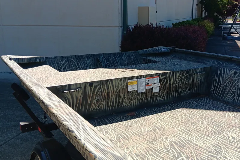 Slide: The Image of 2025 Tracker GRIZZLY 1860 Utility boat with camouflage design, parked outdoors. - 2