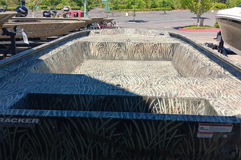 Slide: The Image of 2025 Tracker GRIZZLY 1860 Utility boat with camouflage design in a parking lot. - 3