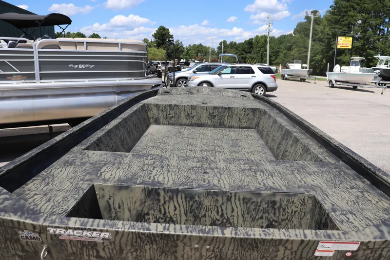 Slide: The Image of 2025 Tracker Grizzly 1860 Utility boat with camouflage design in a parking lot. - 2