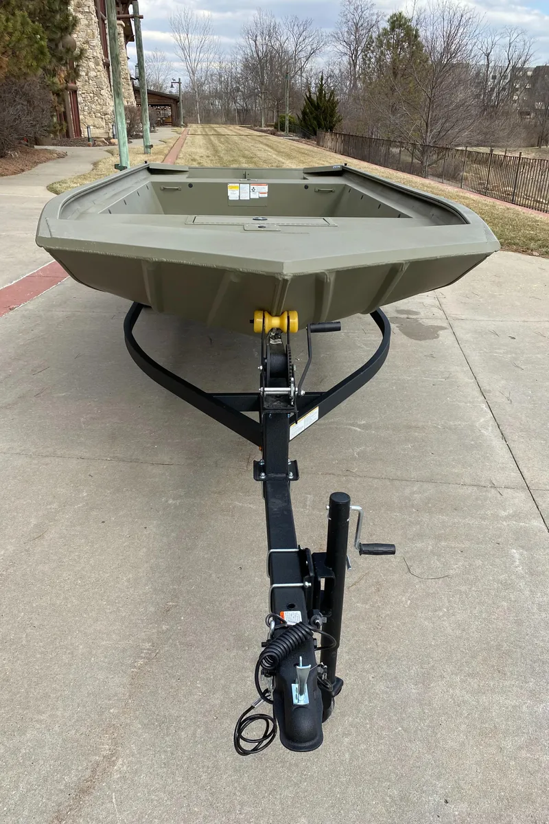 Slide: The Image of 2025 Tracker GRIZZLY 1860 Utility boat on trailer, parked on concrete path. - 2