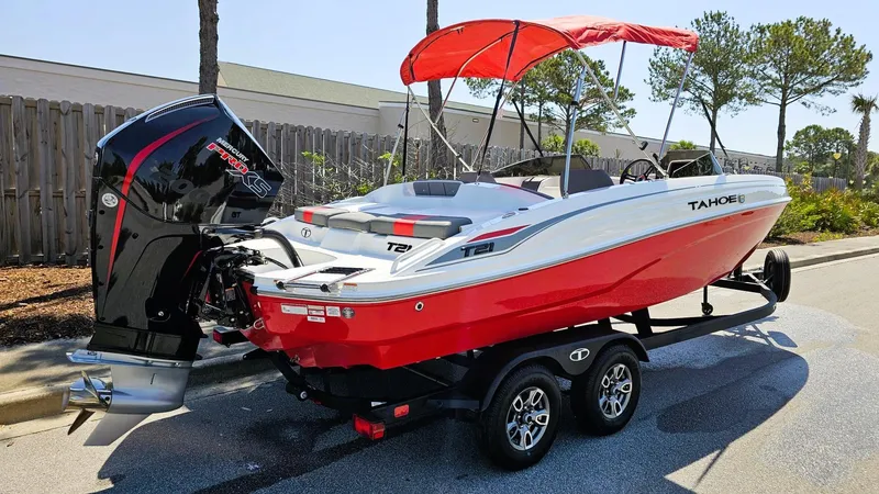 Slide: The Image of 2025 Tahoe T21 boat with red canopy and powerful outboard motor on a trailer. - 2