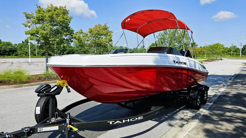 Slide: The Image of 2025 Tahoe T21 boat with red hull and canopy on a trailer, parked outdoors. - 6
