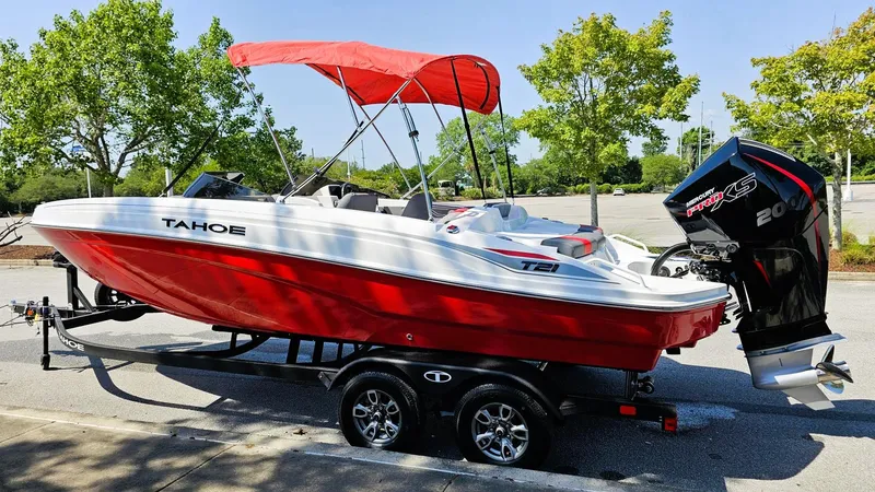 Slide: The Image of 2025 Tahoe T21 boat with red canopy on trailer, parked outdoors. - 7