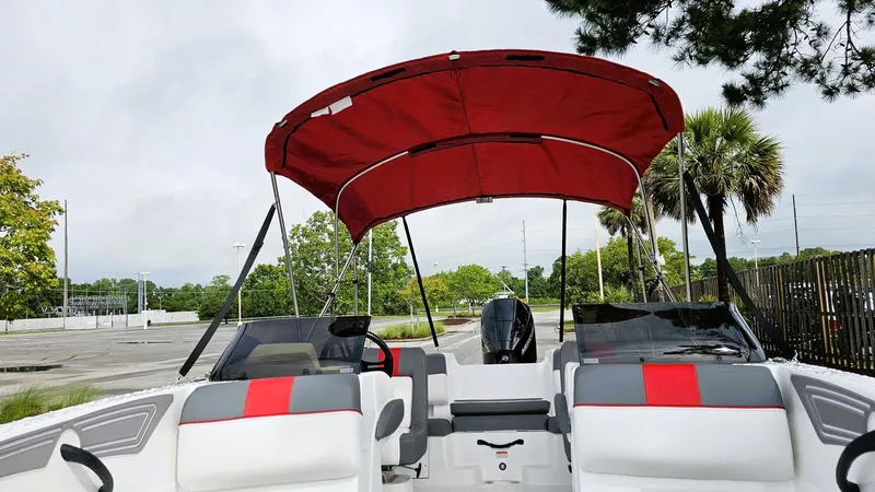 Slide: The Image of 2025 Tahoe T21 boat with red canopy and seating, parked outdoors. - 11