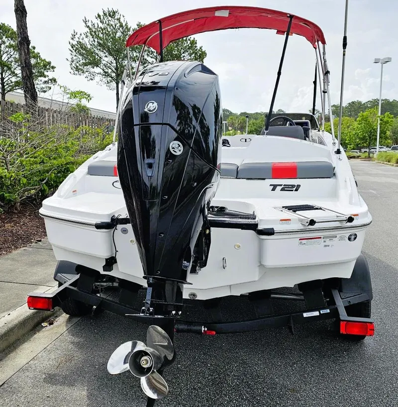 Slide: The Image of 2025 Tahoe T21 boat with outboard motor and red canopy, parked on a trailer. - 12