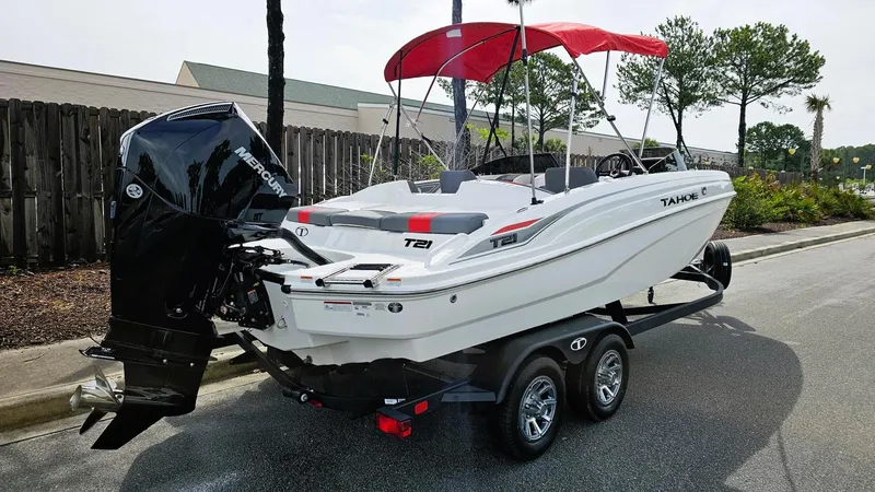 Slide: The Image of 2025 Tahoe T21 boat with red canopy on trailer, parked on street. - 3