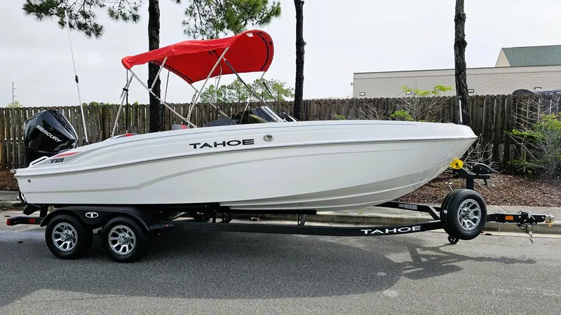 Slide: The Image of 2025 Tahoe T21 boat with red canopy on trailer, parked outdoors. - 4