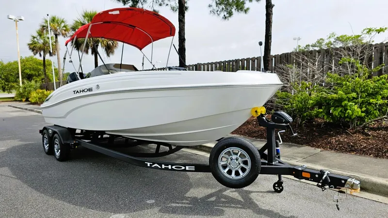 Slide: The Image of 2025 Tahoe T21 boat on trailer with red canopy, parked on a street. - 5