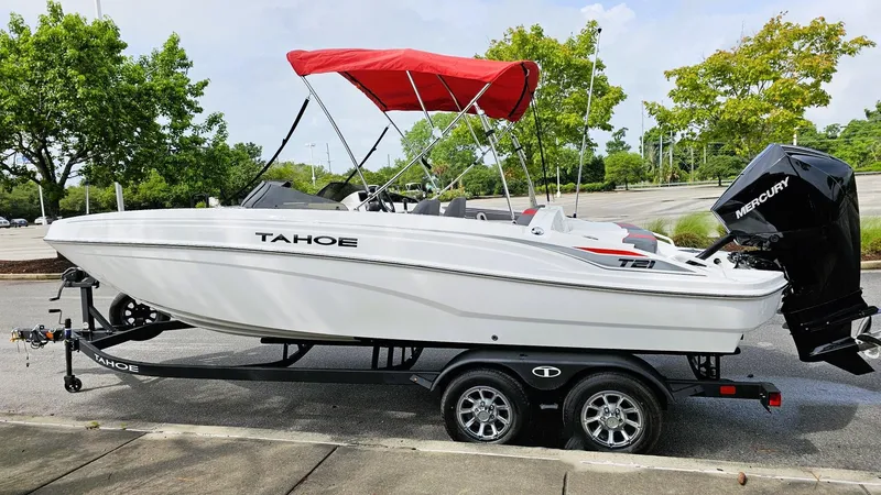 Slide: The Image of 2025 Tahoe T21 boat with red canopy on trailer, parked outdoors. - 8