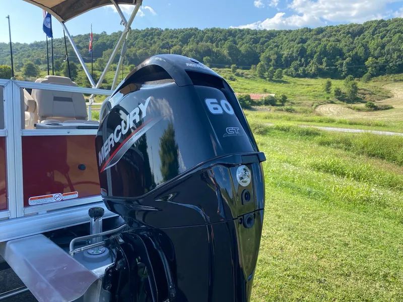 Slide: The Image of 2025 Sun Tracker Bass Buggy 18 DLX with Mercury 60 outboard motor in scenic landscape. - 6