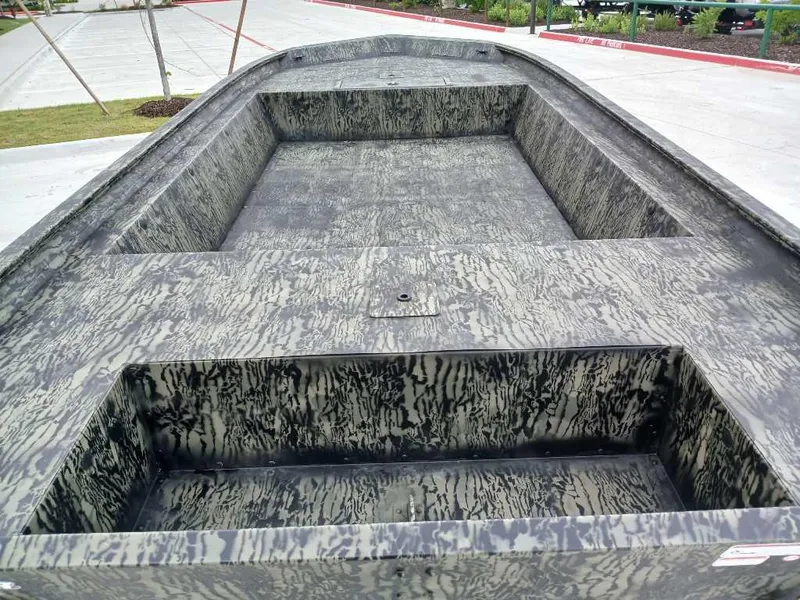 Slide: The Image of 2025 Tracker GRIZZLY 1860 Utility boat with camouflage interior, parked on concrete. - 5