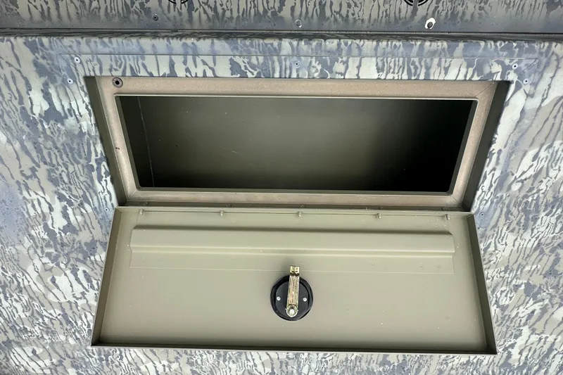 Slide: The Image of Open storage compartment on 2025 Tracker Grizzly 1860 Utility boat, featuring a secure latch. - 19