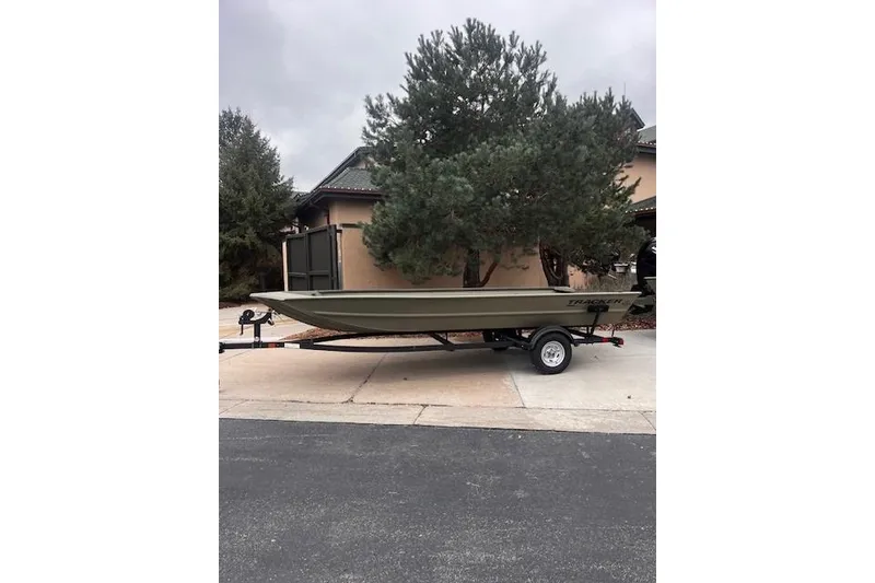 Slide: The Image of 2025 Tracker Grizzly 1860 Utility boat on trailer, parked in driveway. - 17