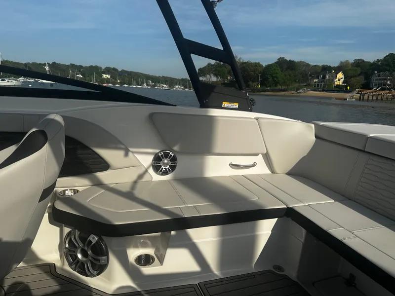 Slide: The Image of 2024 Sea Ray 230SPX boat interior with beige seating and speakers, docked by a scenic shoreline. - 4