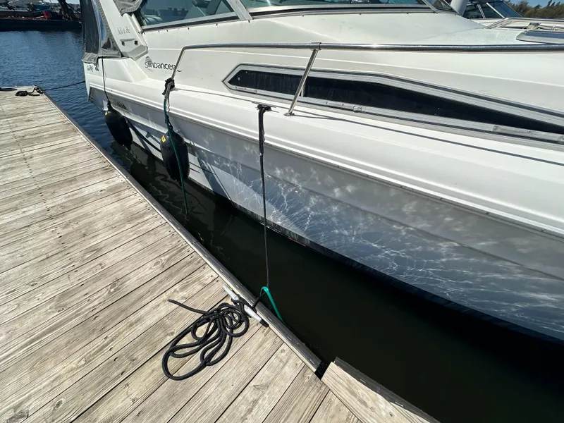 Slide: The Image of 1990 Sea Ray 310 Sundancer docked at a marina, side view with mooring lines. - 10
