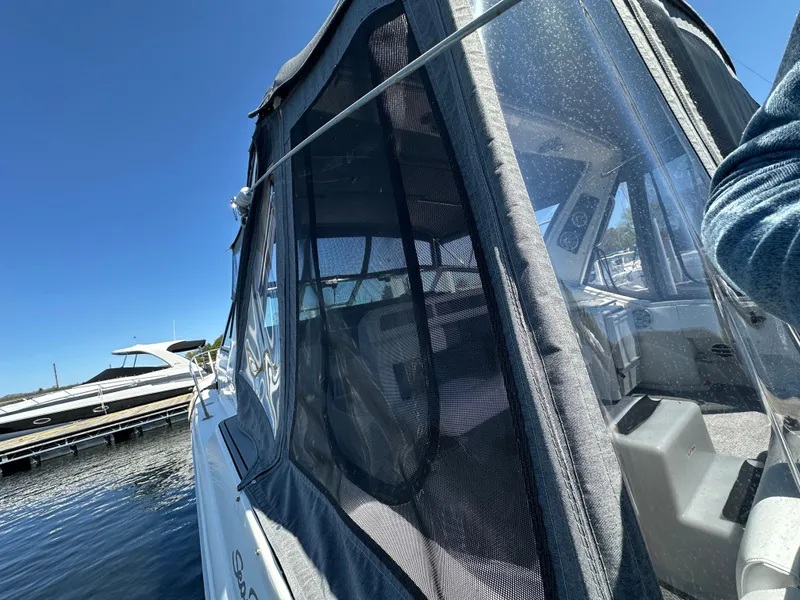 Slide: The Image of 1990 Sea Ray 310 Sundancer boat with enclosed cockpit, docked under clear blue sky. - 13