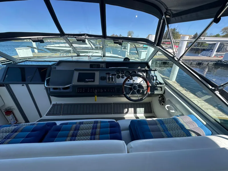 Slide: The Image of 1990 Sea Ray 310 Sundancer cockpit with steering wheel, dashboard, and marina view. - 14
