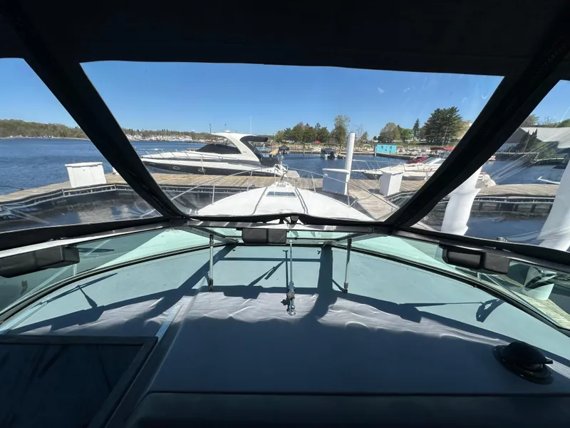 Slide: The Image of 1990 Sea Ray 310 Sundancer cockpit view at marina, clear sky, calm waters. - 26