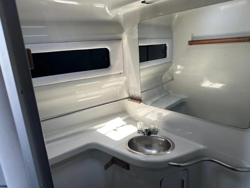 Slide: The Image of 1990 Sea Ray 310 Sundancer bathroom with sink, mirror, and sleek white interior. - 33