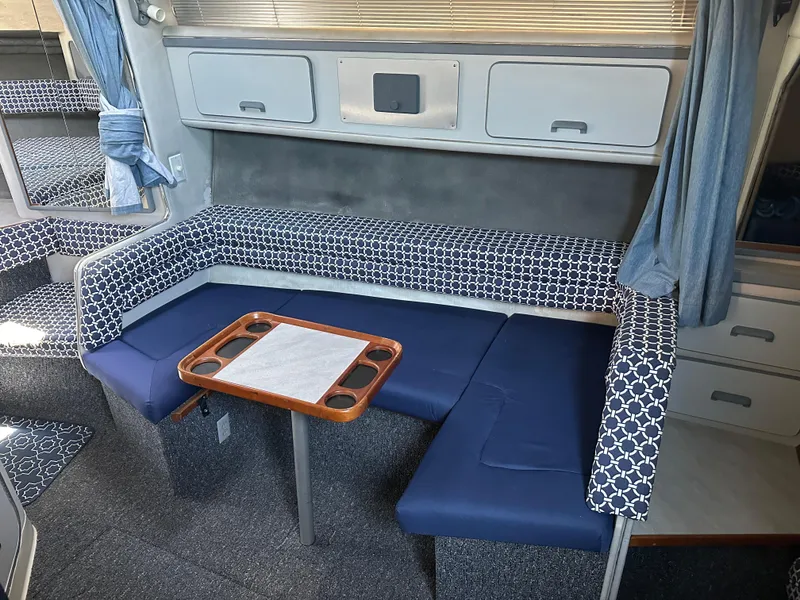Slide: The Image of Interior of 1990 Sea Ray 310 Sundancer with blue seating and wooden table. - 37
