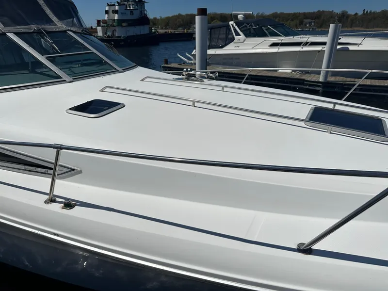 Slide: The Image of 1990 Sea Ray 310 Sundancer docked at marina, showcasing sleek white deck design. - 42